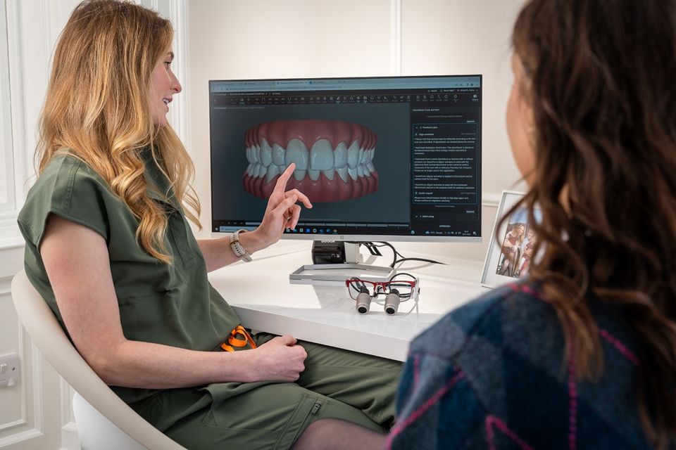 La dentista mostra a una paziente il modello dei denti sullo schermo